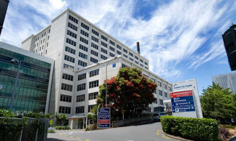 A large white building with many windows. A sign reads "Auckland City Hospital"